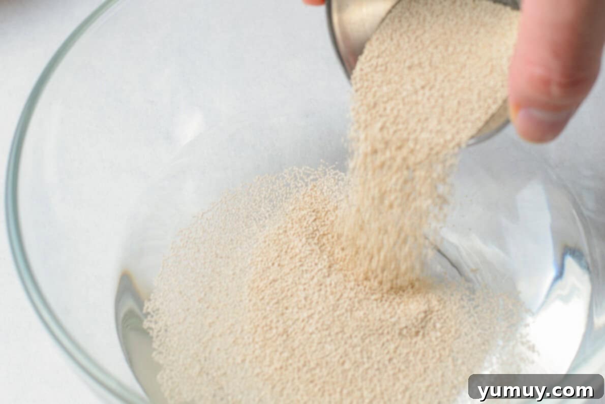 Homemade Krispy Kreme Glazed Donuts 12 a person pouring sugar into a glass bowl.