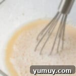 Homemade Krispy Kreme Glazed Donuts 6 a person whisking a liquid into a glass bowl.
