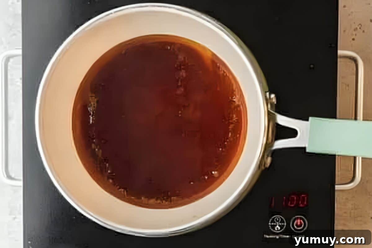 Hot caramel sauce freshly poured and coating the bottom of a round cake pan.