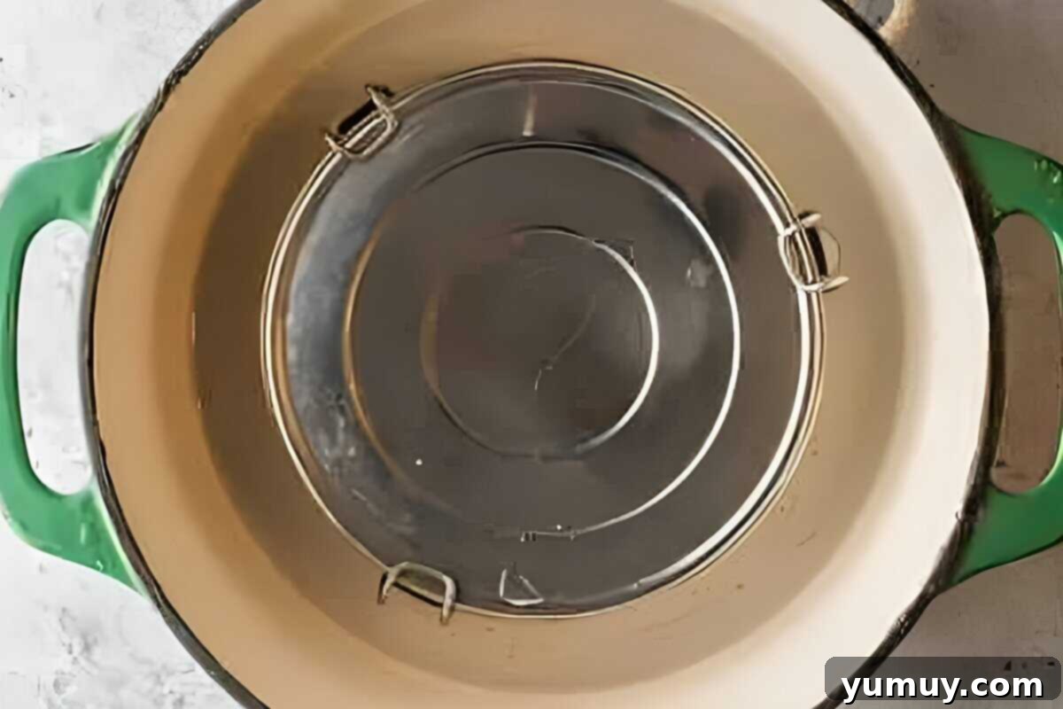 The flan pan, covered with foil, nestled in a water bath within a larger baking pan, ready for the oven.