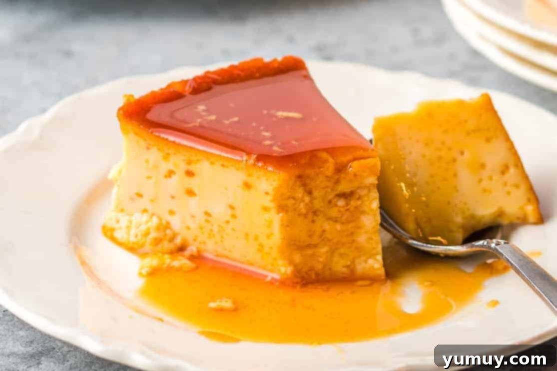 A perfectly sliced piece of flan, adorned with generous caramel topping, presented on a small white plate.