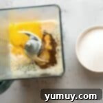 Combining eggs, milk, and vanilla in a blender for the flan custard.