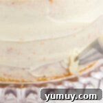 A close-up of piping delicate buttercream rosettes onto an easy homemade wedding cake, showcasing the technique on a glass cake stand.