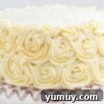 The easy homemade wedding cake, now beautifully adorned with elegant buttercream rosettes, presented on a glass cake stand.