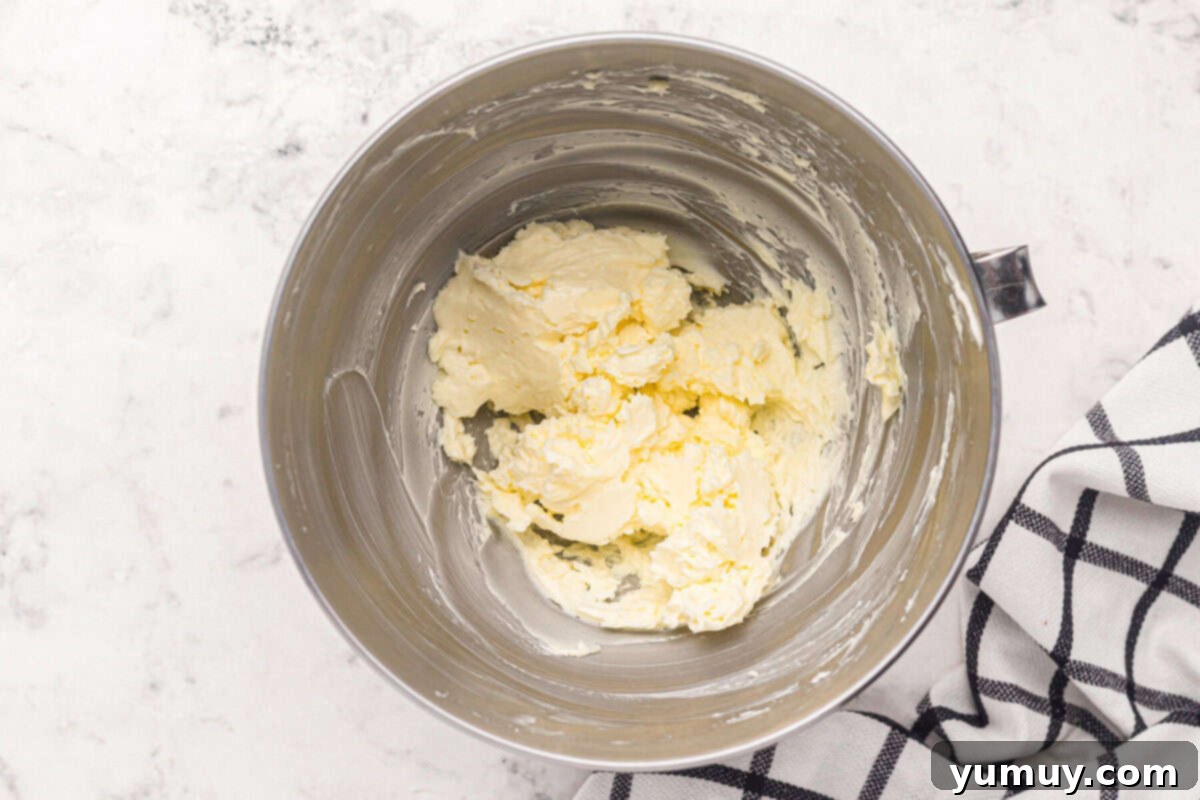 Wet ingredients for easy homemade wedding cake, including butter, vanilla, and egg whites, whipped to a smooth consistency in a stainless steel mixing bowl.