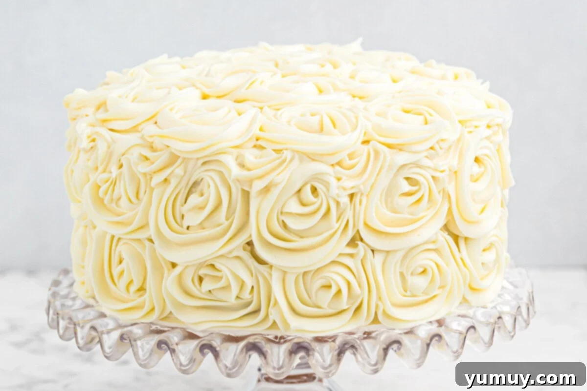 The fully decorated easy homemade wedding cake, completely covered in delicate rosettes, displayed beautifully on a glass cake stand.