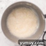 Foamy egg mixture for easy homemade wedding cake, lightly whisked in a stainless steel mixing bowl, ready for the next step.