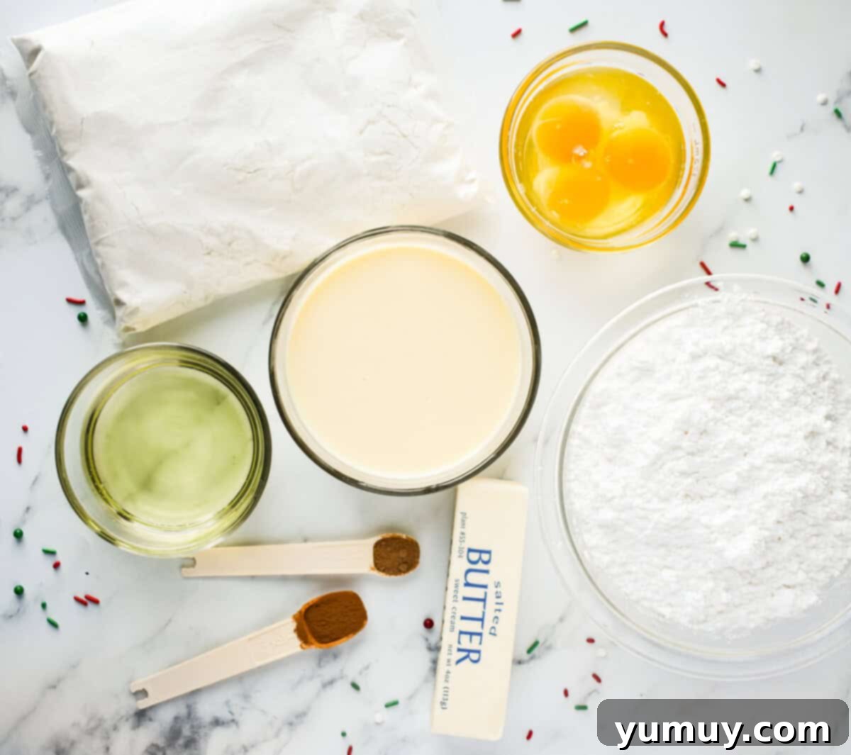 An overhead view of the carefully arranged ingredients for making an eggnog sheet cake, showcasing fresh eggs, a box of cake mix, and a carton of rich eggnog.