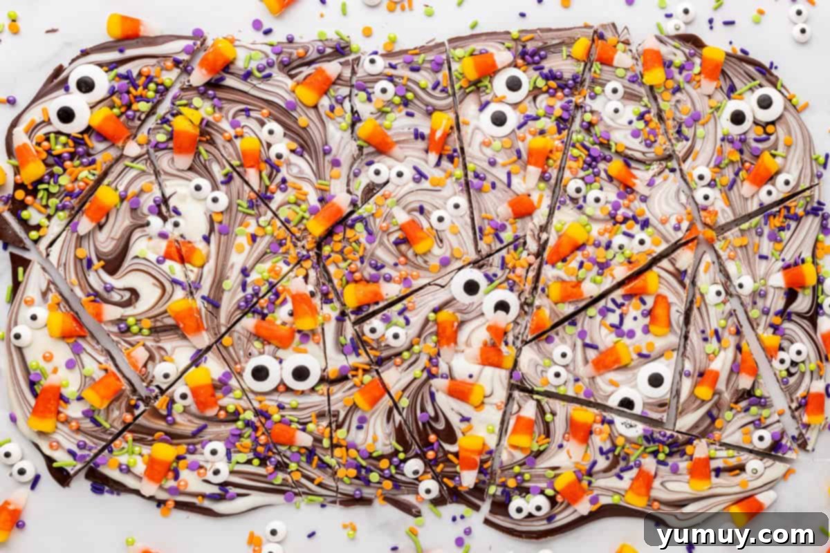 Halloween chocolate bark with monster eyes and candy corn, broken apart into chunks.