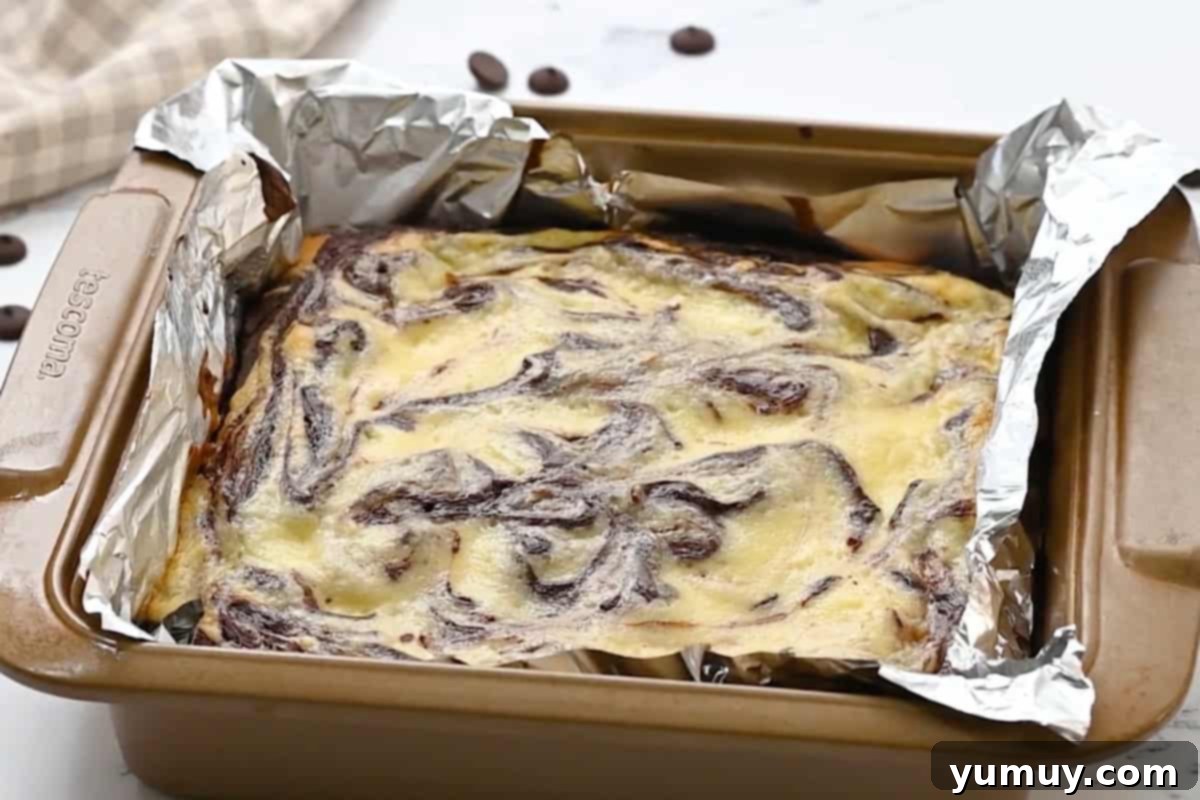 freshly baked cream cheese brownies in a foil-lined baking pan.