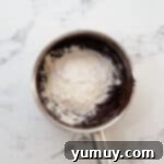 adding flour, baking soda, and salt to wet ingredients for brownies in a saucepan.