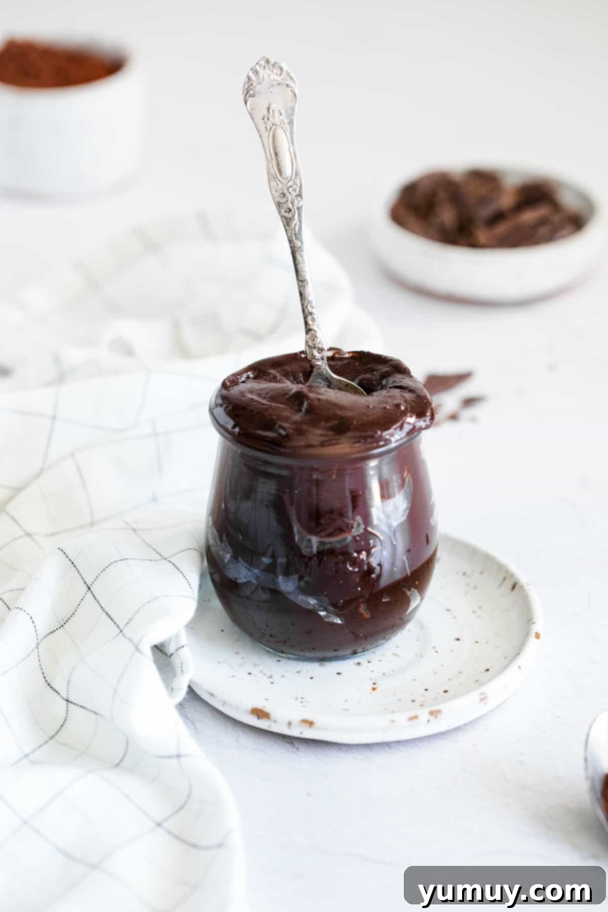 Velvety Homemade Chocolate Hazelnut Spread 2 A glass jar filled with rich, creamy homemade chocolate hazelnut spread, with a spoon nestled inside, ready to be enjoyed.