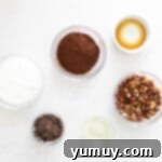 Velvety Homemade Chocolate Hazelnut Spread 5 Small bowls filled with fresh ingredients for homemade Nutella, including raw hazelnuts, sugar, and chocolate.