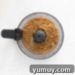 Velvety Homemade Chocolate Hazelnut Spread 6 A layer of finely ground hazelnuts at the bottom of a food processor bowl, ready for the next ingredients.