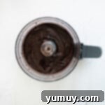 Velvety Homemade Chocolate Hazelnut Spread 7 All the ingredients for homemade Nutella blending together in a food processor, creating a smooth chocolatey mixture.