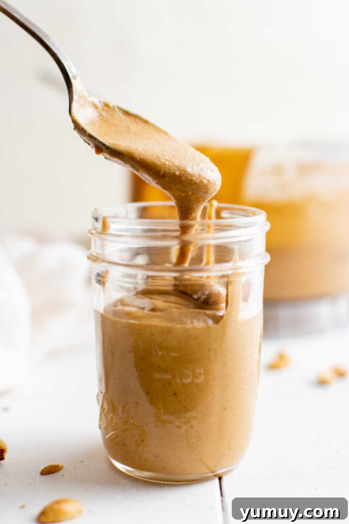 Craft Your Own Peanut Butter 2 A spoon dipping into a jar of homemade peanut butter, showcasing its creamy texture and rich color.