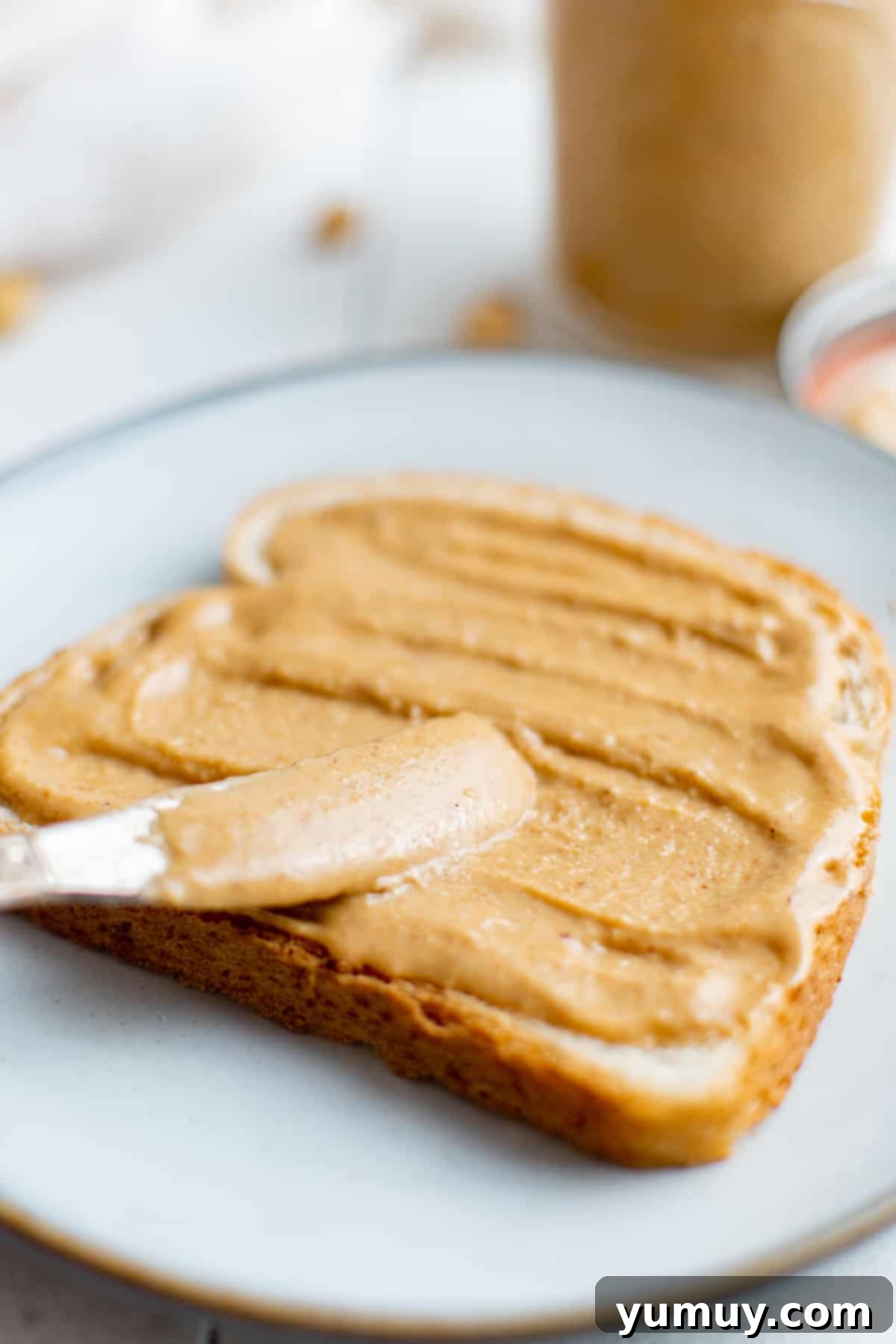 Craft Your Own Peanut Butter 3 Spreading creamy homemade peanut butter onto a piece of toasted bread, ready for a delicious breakfast or snack.