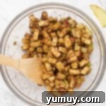 Preparing apples with lemon juice and pumpkin pie spice in a large bowl for Instant Pot apple crisp.