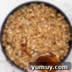 Drizzling maple syrup over the oat topping of the apple crisp before cooking.