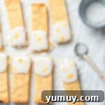 Freshly iced lemon shortbread cookies, beautifully garnished with lemon zest, ready to be enjoyed.