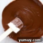 Festive Pretzel Bark 5 Melted chocolate in a glass bowl with a rubber spatula, ready for mixing.