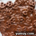 Festive Pretzel Bark 7 Melted chocolate and pretzels spread out on a parchment-lined baking sheet.