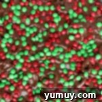 Festive Pretzel Bark 8 Red and green M&Ms sprinkled over melted chocolate and pretzels on a lined baking sheet.