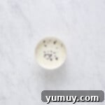 A bowl of rich chocolate ganache with a spoon, ready for drizzling.