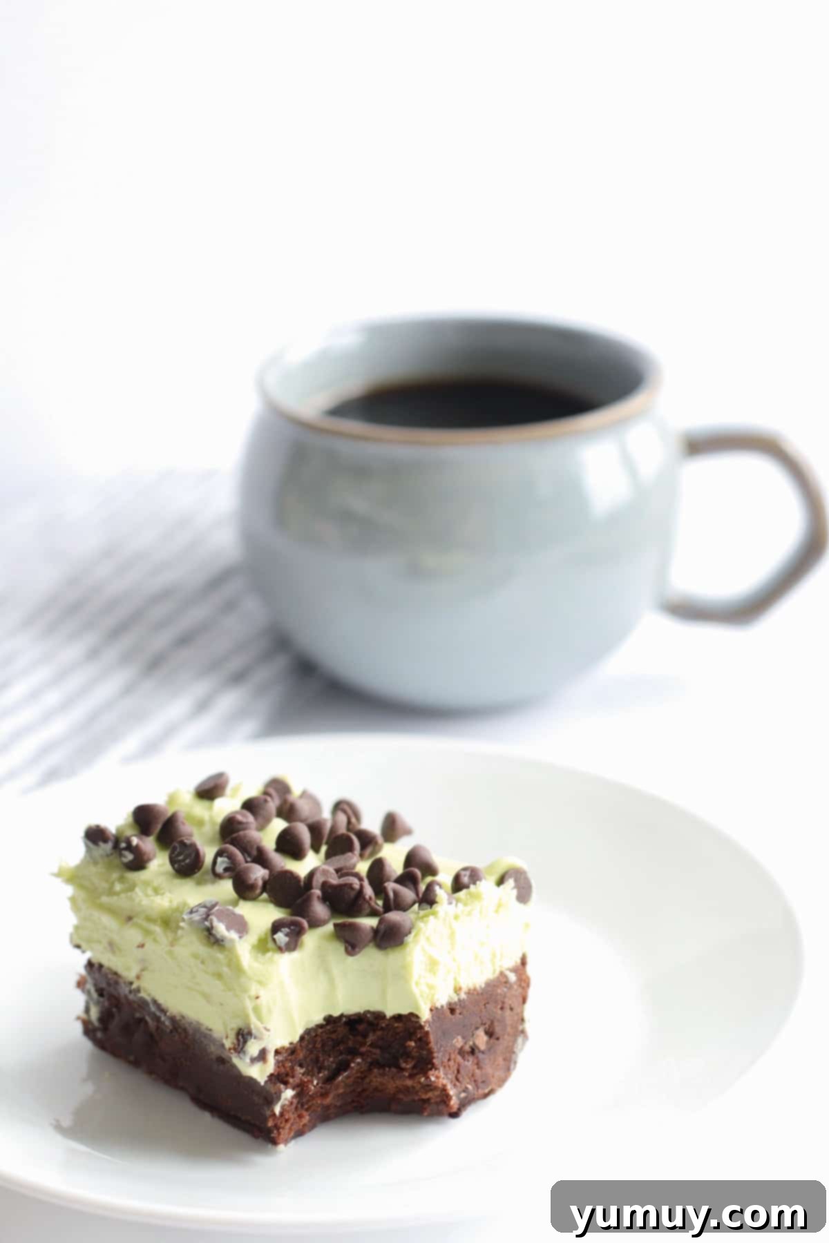 mint chocolate chip brownie on a plate with a cup of coffee