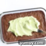 spreading mint frosting on top of baked brownies