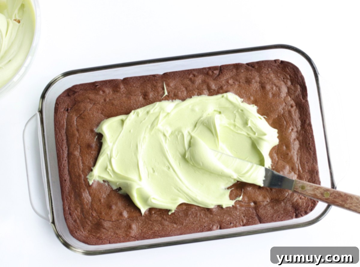 spreading mint frosting on top of baked brownies