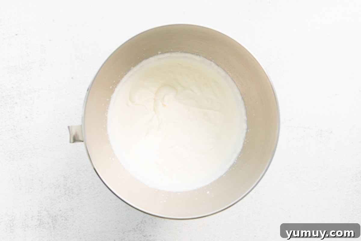 No-Churn Mint Chip Bliss 9 Perfectly whipped heavy cream, forming stiff peaks in a stainless steel mixing bowl, ready to become the base of a decadent no-churn ice cream.