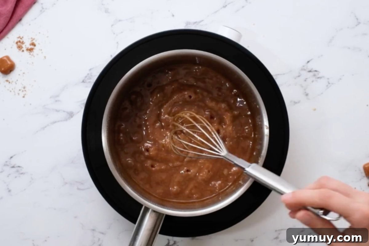 Whisking the thickened brown sugar caramel in a saucepan after vanilla has been added.