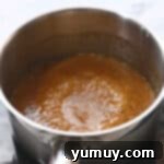 Simmering brown sugar caramel in a saucepan, bubbling gently.