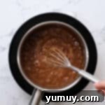 Stirring brown sugar caramel in a saucepan with a whisk, after vanilla has been added.