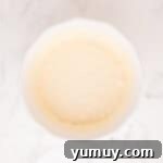 Smooth and creamy cheesecake filling, ready to be spread, in a white mixing bowl.