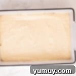 Creamy cheesecake filling meticulously spread over the crescent dough base in a rectangular baking pan.
