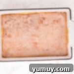 Cinnamon sugar evenly sprinkled over freshly baked churro cheesecake bars in a rectangular baking pan, awaiting the final broil.