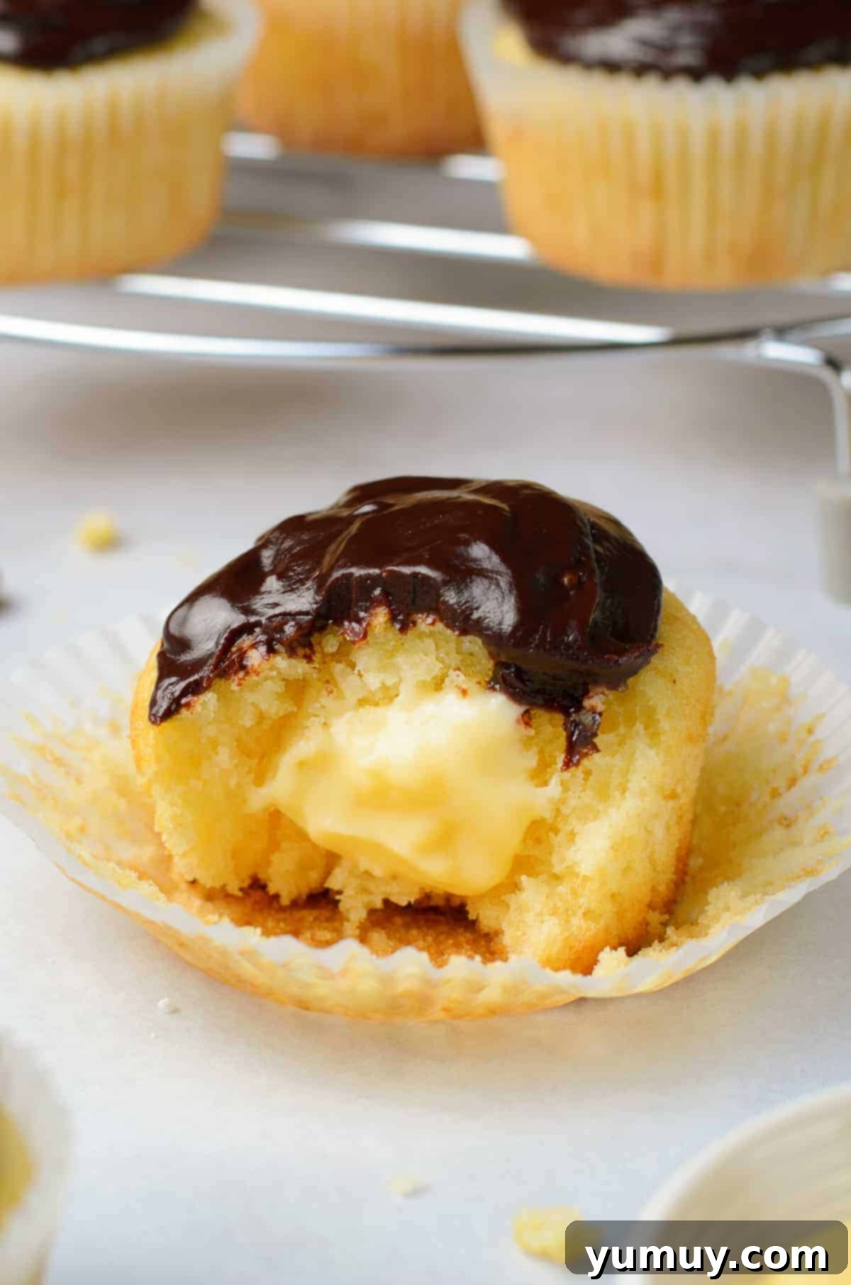 Rich, creamy custard filling revealed in the center of a Boston cream pie cupcake, highlighting its luscious texture.