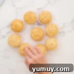 Small cake pieces being placed back over the pastry cream-filled cupcakes to seal the centers.