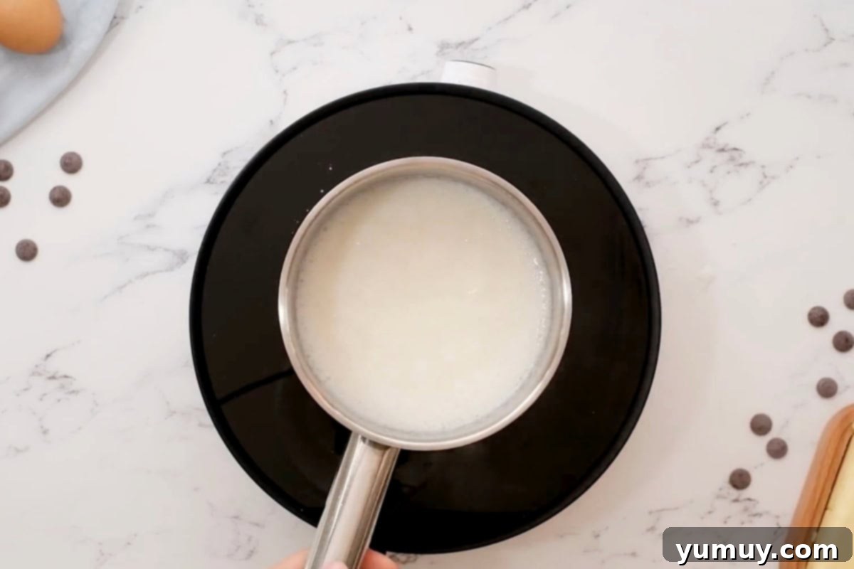 Cornstarch, sugar, and milk being smoothly mixed in a saucepan on the stove.