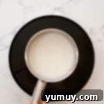 Cornstarch and milk being mixed in a saucepan, starting the pastry cream process.