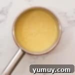 Pastry cream actively cooking and thickening in a saucepan on the stove.