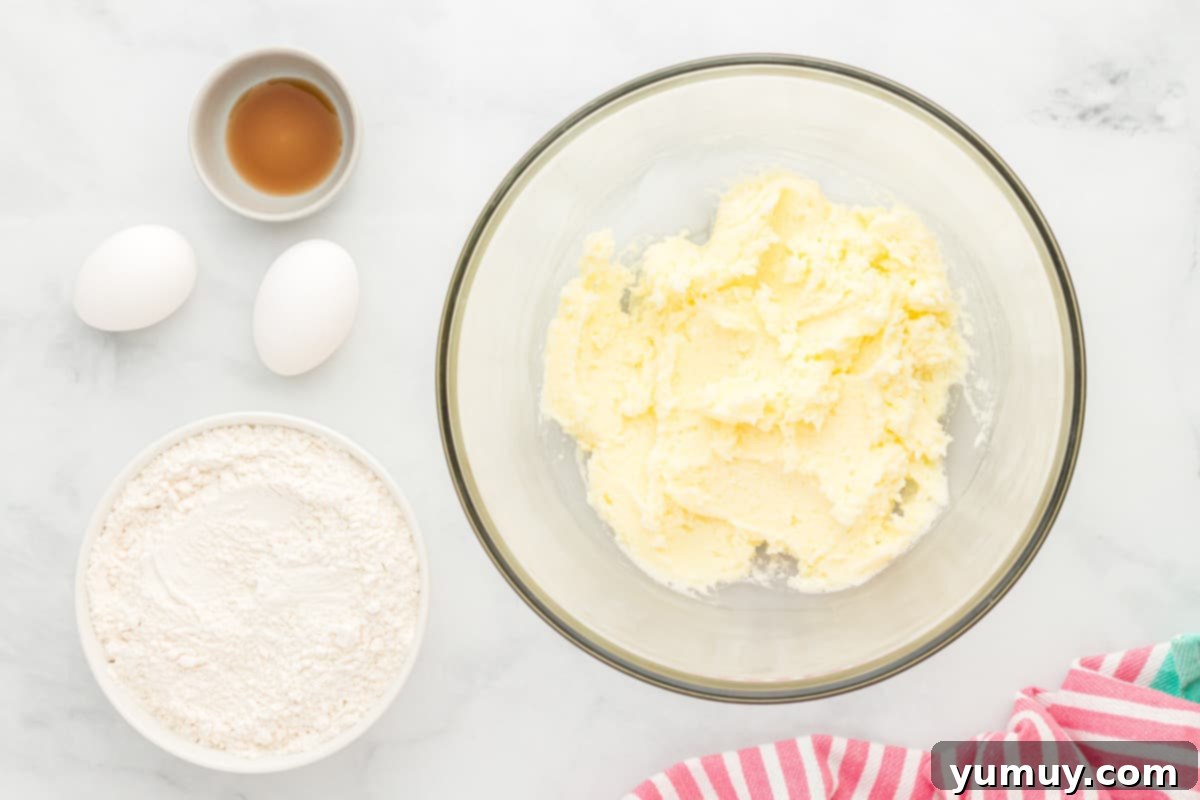 The process of creaming butter and sugar, with eggs and vanilla on the side, ready to be incorporated into the dough.