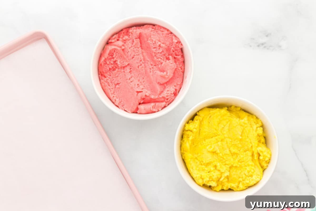 Two separate bowls filled with beautifully colored cookie dough: one vibrant pink and strawberry-flavored, the other bright yellow and lemon-flavored.