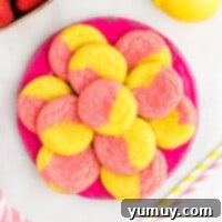 A plate of freshly baked pink and yellow swirl cookies with fresh strawberries and lemon slices.