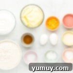 A selection of baking ingredients laid out on a marble surface, including flour, sugar, butter, and eggs.