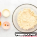 Prepared cookie dough in a bowl, with smaller bowls of Jell-O powder and lemon zest ready for flavoring.