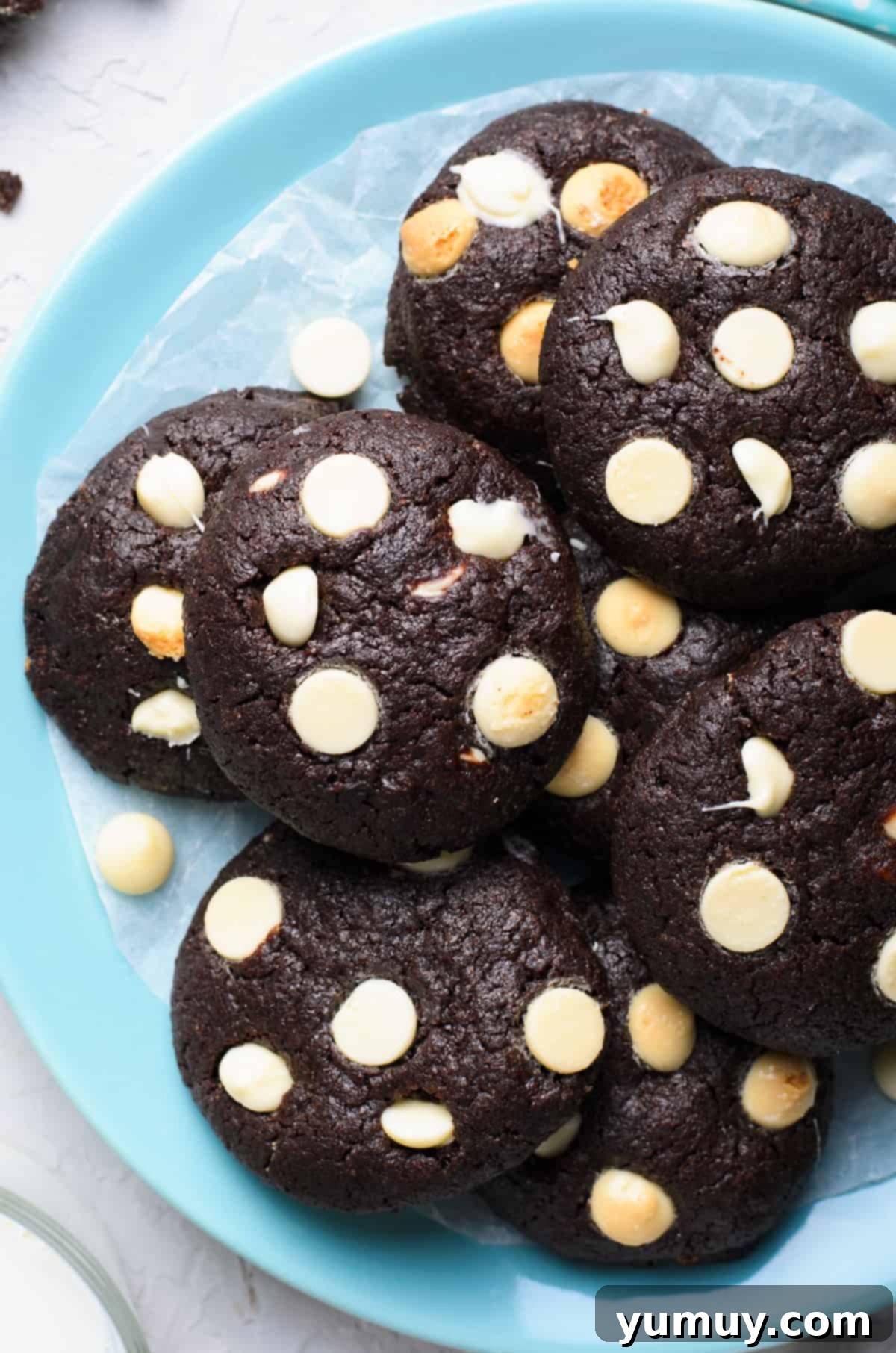 Up close view of a stack of rich chocolate cookies with melted white chocolate chips, showcasing their fudgy texture.