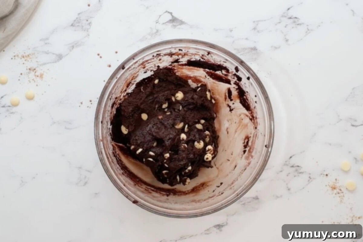 White chocolate chip cookie dough in a glass bowl, with chips evenly folded in.
